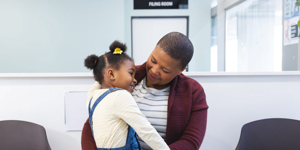 A woman holding her child in the waiting room of a health centre or clinic.